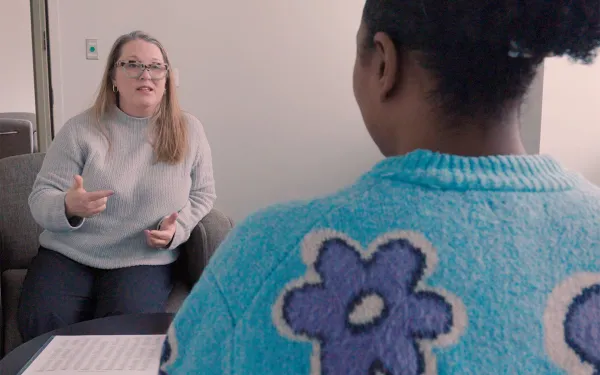 A therapist speaks to a client as the two of them sit opposite each other in a room